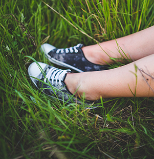 image of two feet wearing sneakers in the grass