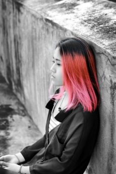 girl with pink hair leaned against a wall