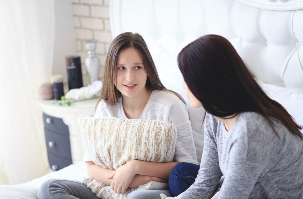 A teenage girl sitting in bed and talking to her mother