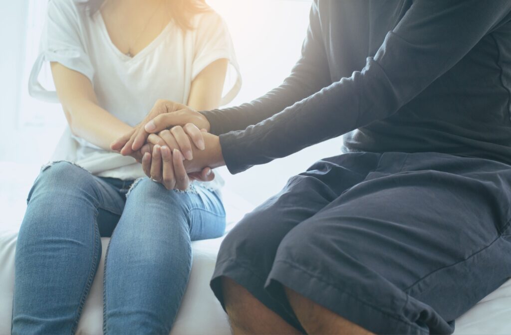 Two people sitting, holding hands in connection to have an open dialogue about mental health